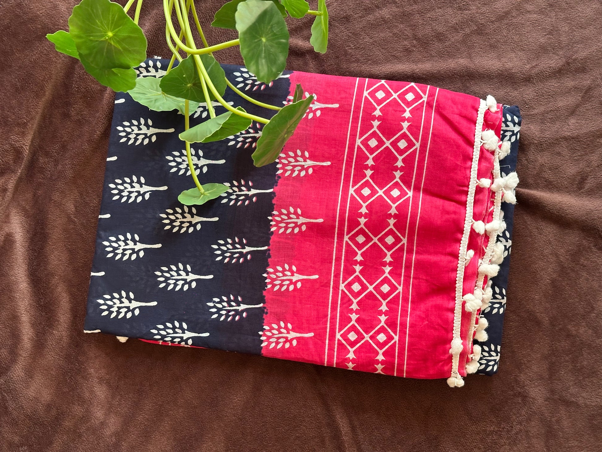 Mandhara_Bagru print mul mul cotton saree from saree from thambai.pink and navy patterned fabric on a brown surface with flowers.