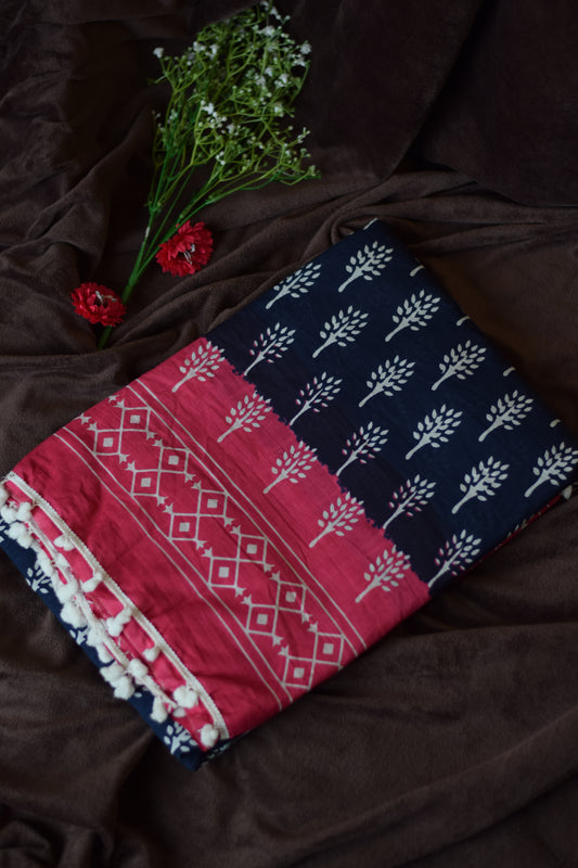 Mandhara_Bagru print mul mul cotton saree from saree from thambai.pink and navy patterned fabric on a brown surface with flowers.