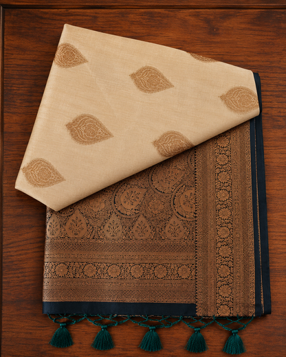 Cream-beige butter silk saree featuring a heavily woven navy blue antique zari pallu with tassels from Thambai online store.