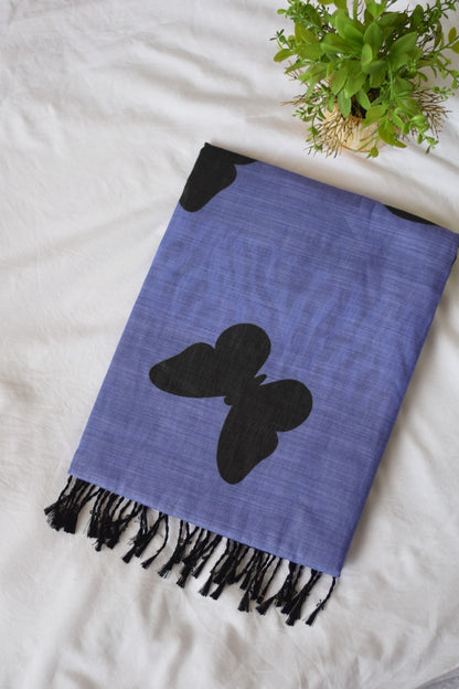 saree friom thambais's Blue Chanderi Linen Cotton with black butterfly design on a white surface with a plant in the corner