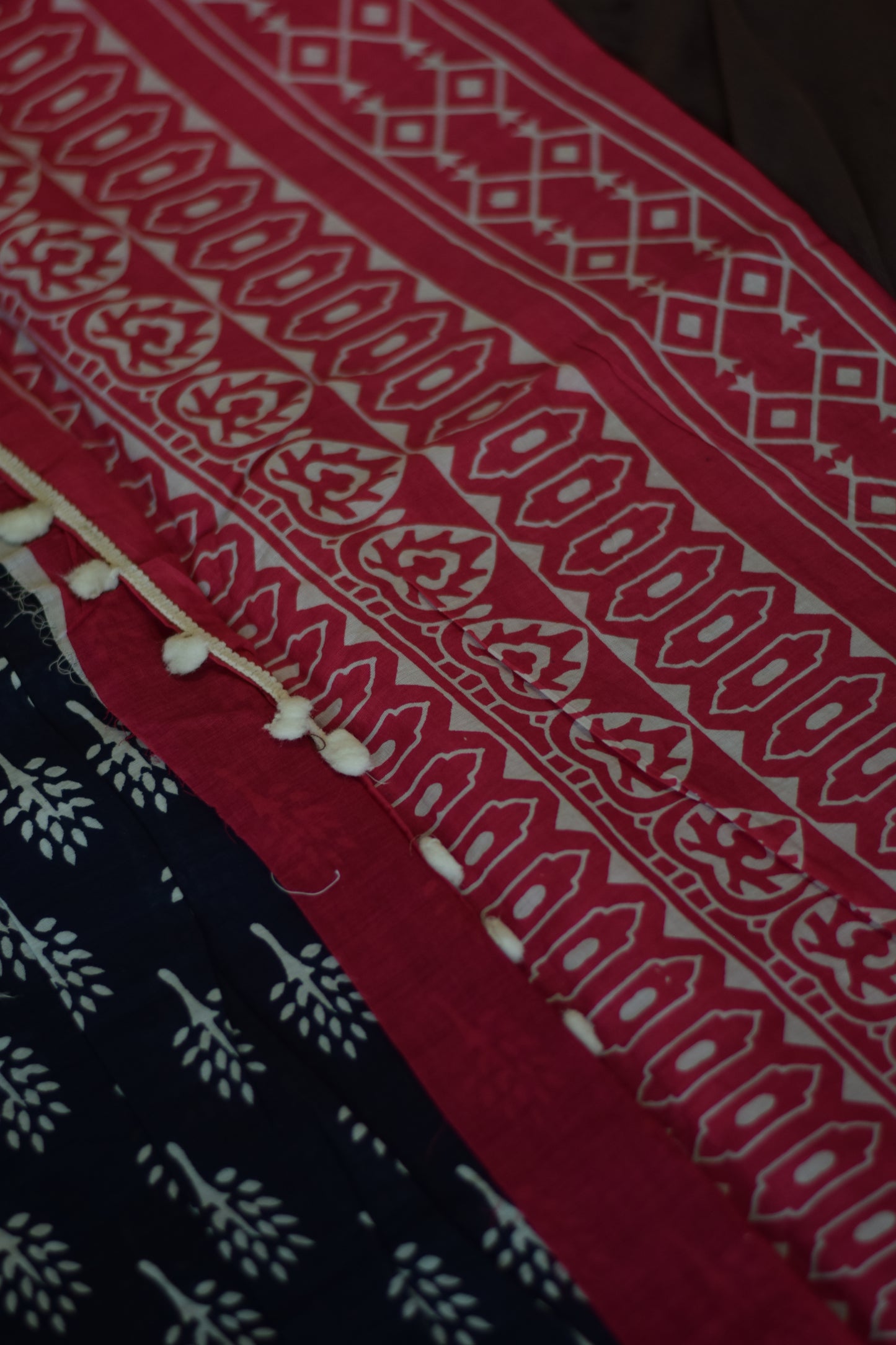 Close-up of Mandhara_Bagru print mul mul cotton saree from saree from thambai.pink and navy patterned fabric on a brown surface 