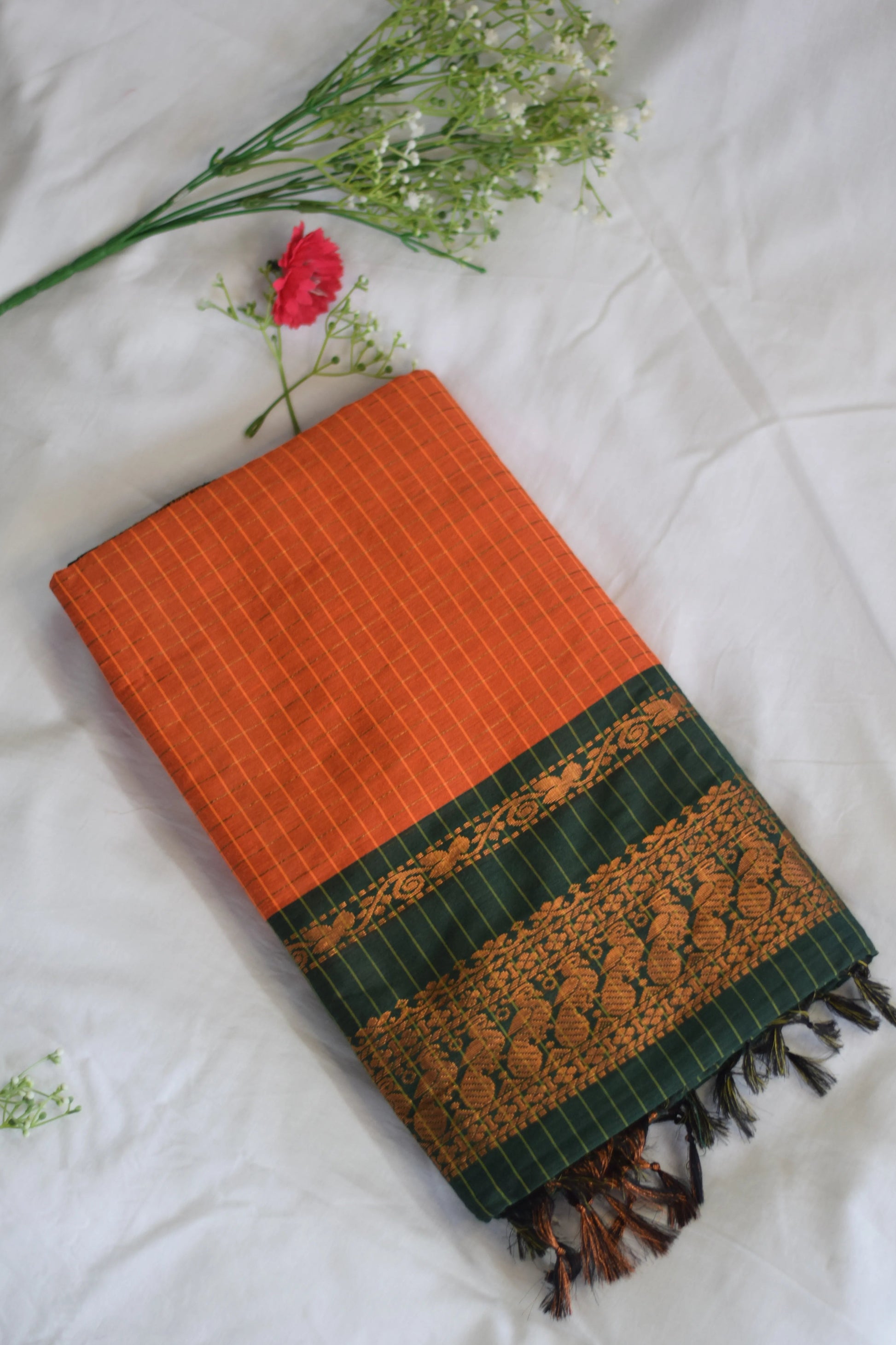 Orange and green kalyani cotton fabric saree with floral decorations on a white background