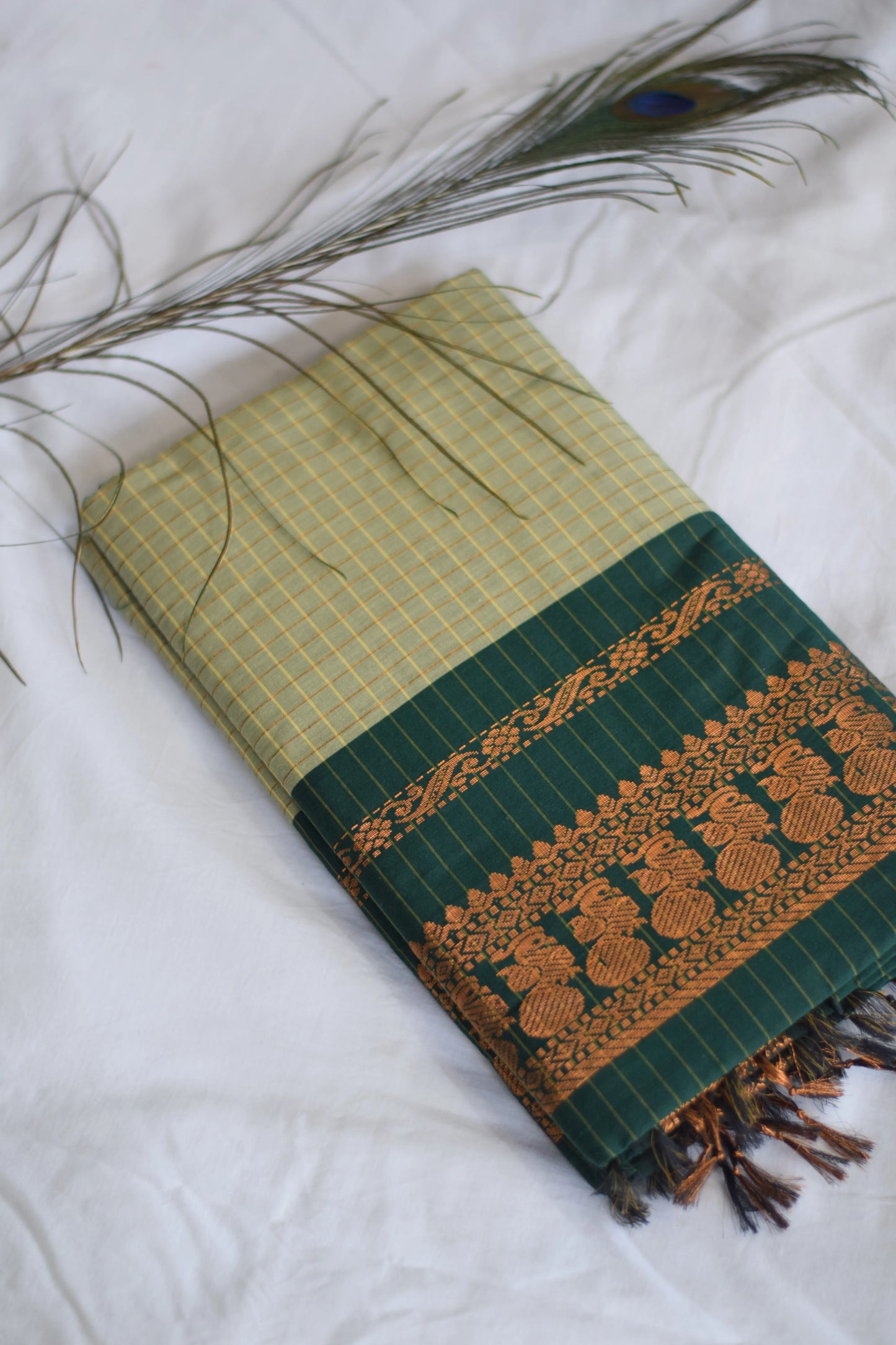 Green and gold patterned fabric with tassels on a white background