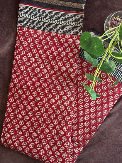 Kunkuma_Ajrakh Print Saree from saree from thambai .Red fabric with white floral pattern on a brown surface