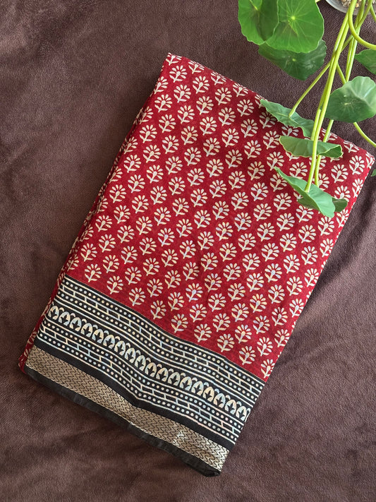 Kunkuma_Ajrakh Print Saree from saree from thambai .Red fabric with white floral pattern on a brown surface