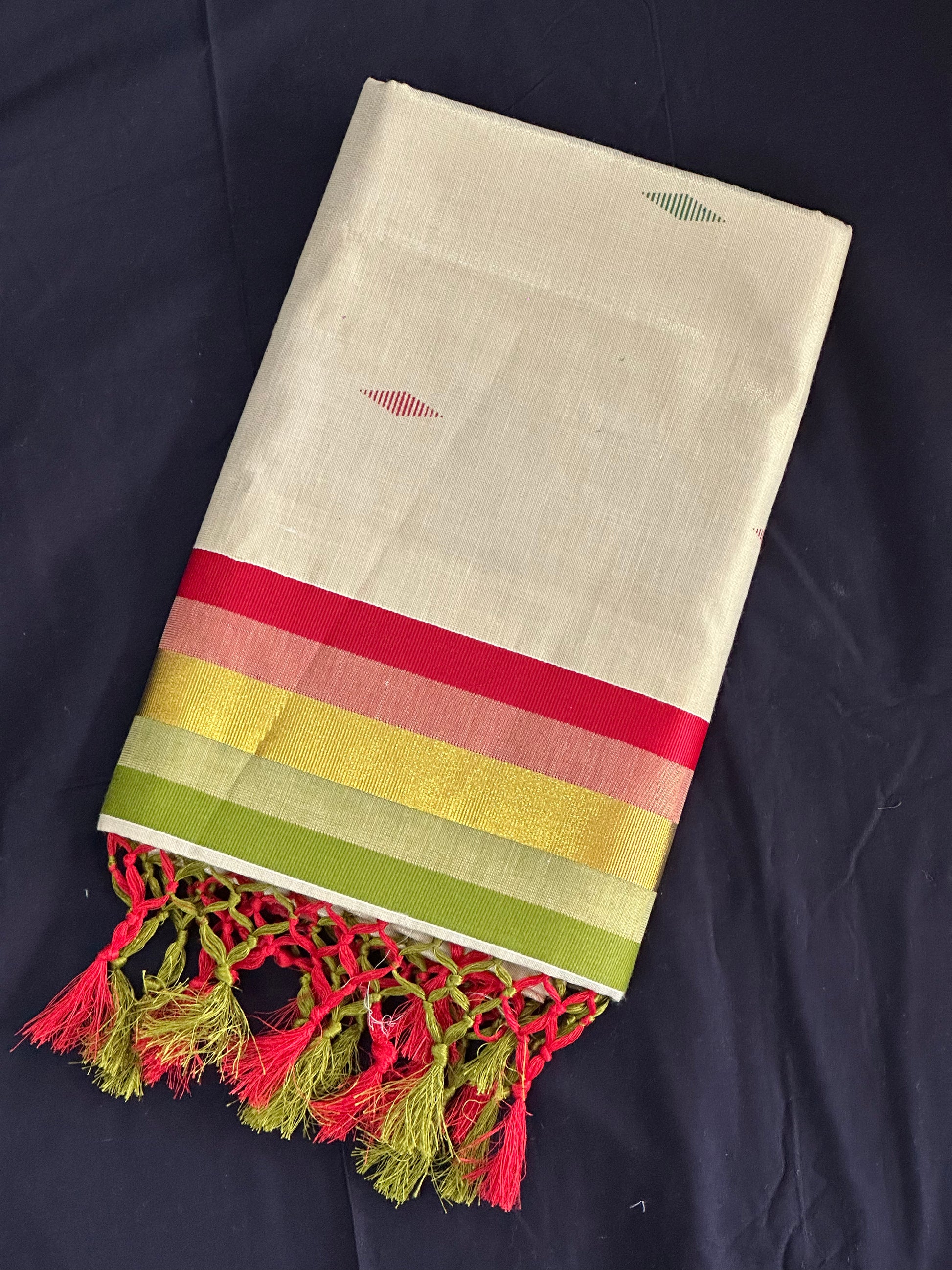 Paarijaatham_Multicolor Border Kerala traditional tissue set saree from saree from thambai with colorful stripes and tassels on a dark background