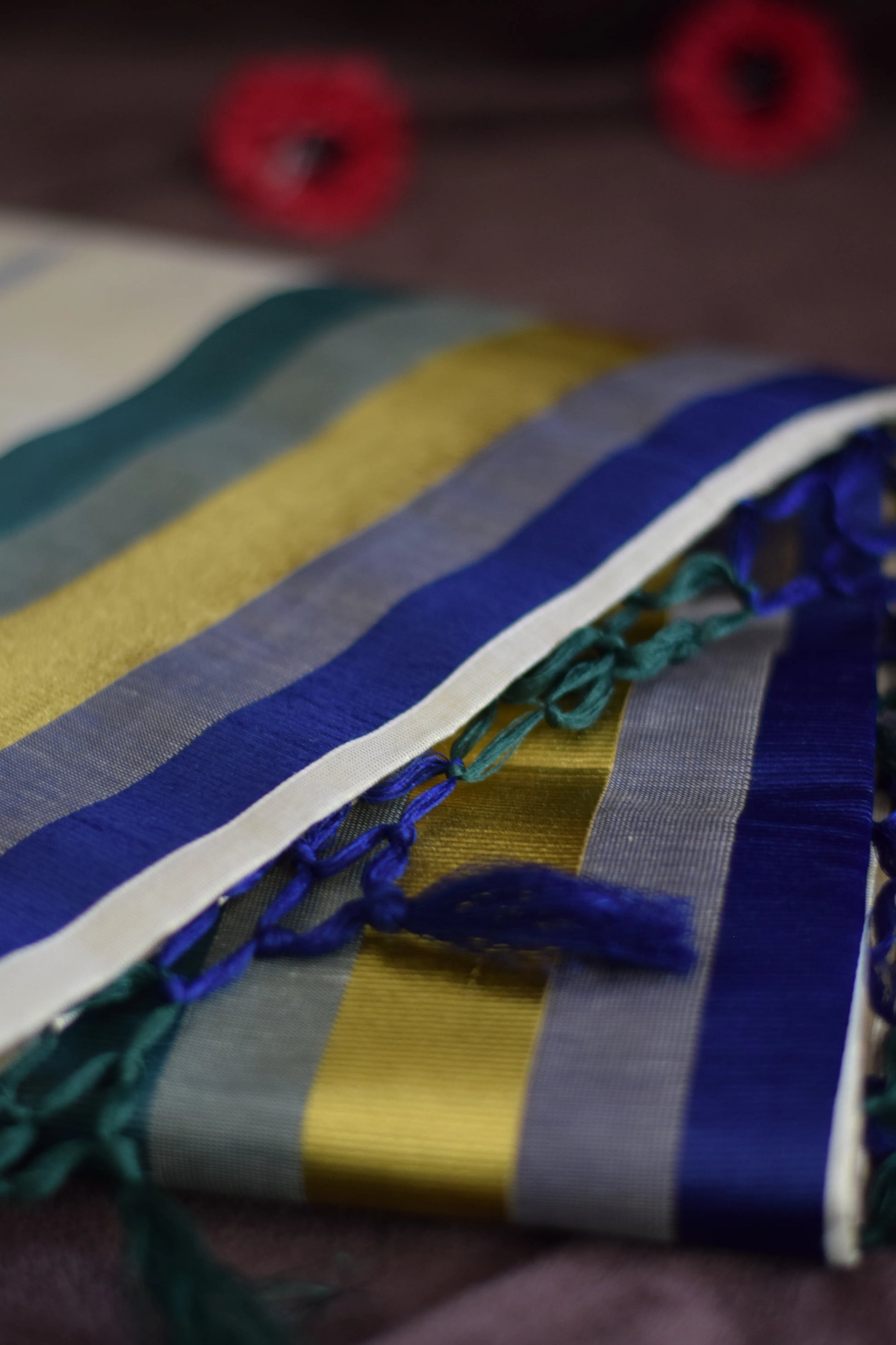 Paarijaatham_Multicolor Border Kerala traditional tissue set saree from saree from thambai with colorful stripes and tassels on a dark background